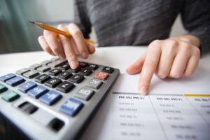 Mão calculando em calculadora os gastos empresariais de uma cultura financeira sustentável