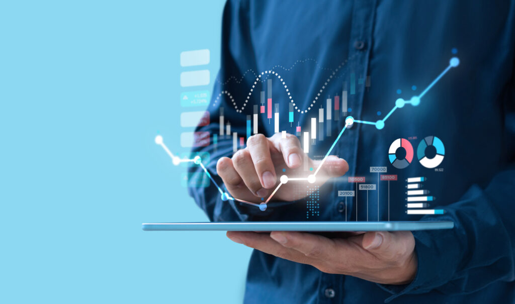 Homem usando tablet com gráficos e dados financeiros, simbolizando expansão empresarial por meio de análise de mercado e uso de tecnologia.